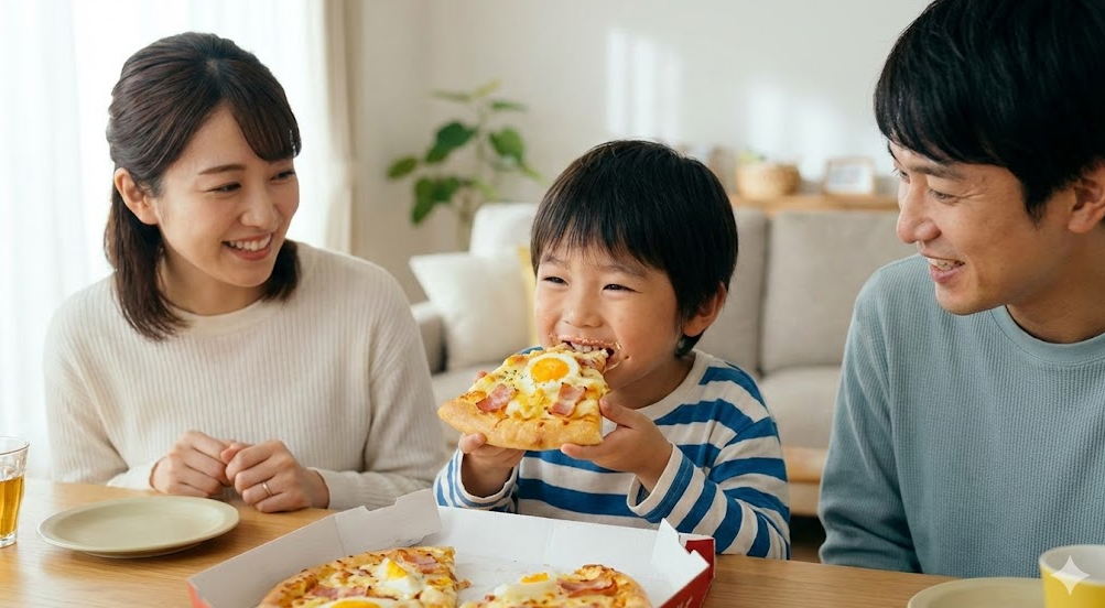 日本の家族が自宅でピザハットの「とろっとカルボナーラピザ」を囲み、男の子が笑顔でピザを食べている温かい食卓の風景。