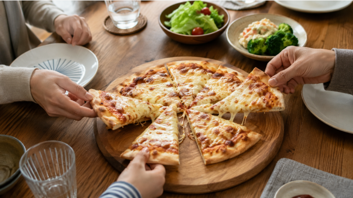 日本の家庭の食卓で複数人がチーズピザをシェアする様子